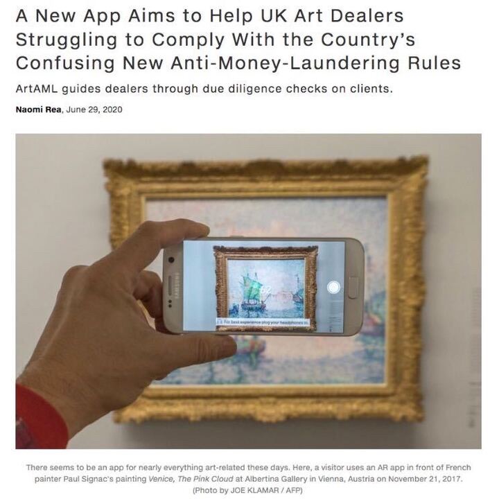 Image of a person holding a smartphone in front of a framed painting